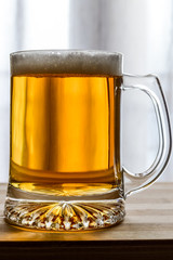 mug of fresh light beer on wood, back lit closeup