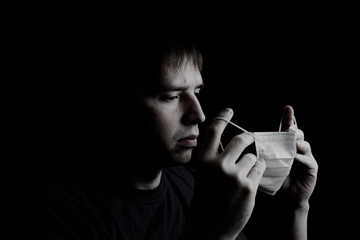 Fototapeta premium man with medical face mask portrait close up illustrates pandemic coronavirus disease on dark background. Covid-19 outbreak contamination concept.