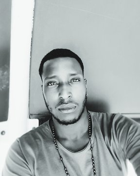 Close-up Portrait Of Young Man Wearing Bead Necklace By Wall