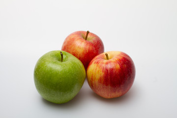 Three apples, one green and two red-yellow on a light background