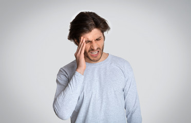 Man suffering from headache, on light background