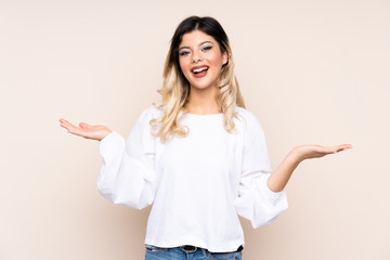 Teenager girl isolated on beige background with shocked facial expression