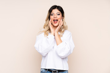 Teenager girl isolated on beige background shouting and announcing something