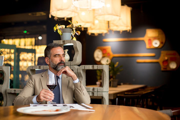 Handsome mature man drinking red wine during lunch