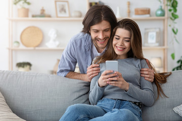 Cheerful couple watching photos on modern phone