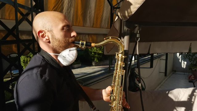 Man at home in quarantine with mask plays music from the windows - italian flash mob during pandemic of n-cov19 Coronavirus