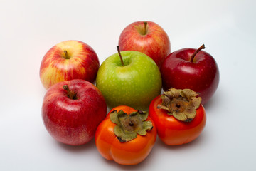 Five apples and two persimmons on a light background