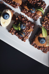 Chocolate dessert with nuts and fresh berries. Sweet snack for coffee biscuit in glaze and nut crumbs with fruit.
