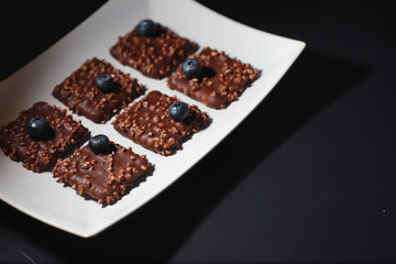 Chocolate dessert with nuts and fresh berries. Sweet snack for coffee biscuit in glaze and nut crumbs with fruit.