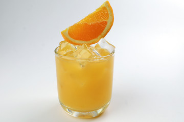 Fresh yellow orange juice in glass with orange slice and ice cube on white background