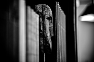 scultura di testa di legno africana in mezzo a un a libreria densa di libri