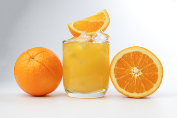Fresh yellow orange juice in glass with whole sliced orange fruit and ice cube on white background