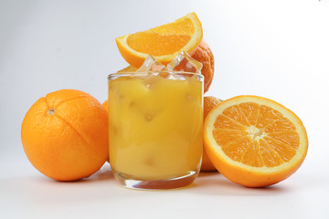 Fresh yellow orange juice in glass with whole sliced orange fruit and ice cube on white background