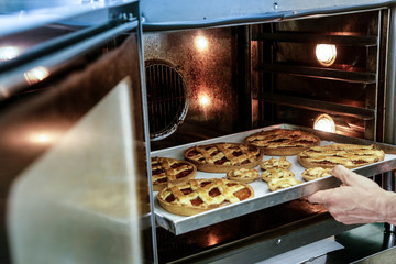 crostata appena pronta in vassoio tenuto in mano da chef che la tira fuori dal forno