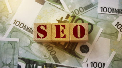 SEO - wooden blocks with letters, search engine optimization SEO concept, top view on 100 euro...