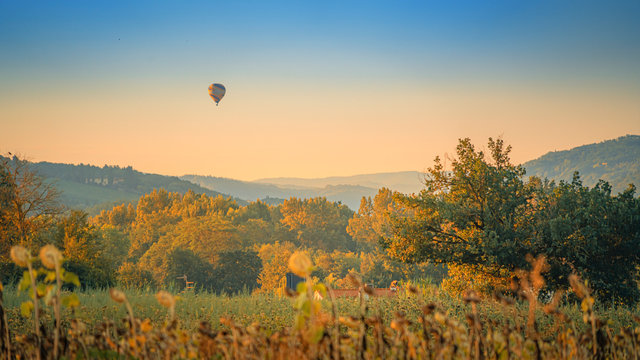 Summer sunrise over the fields and rolling hills with air balloon. Travel destination Chianti, Tuscany