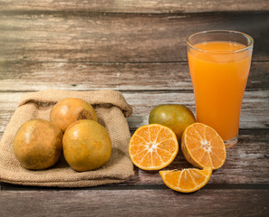 Glass of orange juice and oranges on wooden background. Orange juice on table close-up