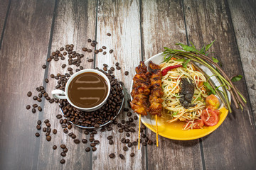 Papaya Salad with Grilled Chicken and Hot Coffee On a wooden background.