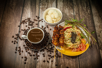 Papaya Salad with Grilled Chicken and Hot Coffee On a wooden background.