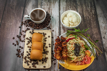 Papaya Salad with Grilled Chicken and Hot Coffee On a wooden background.