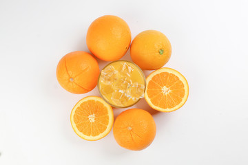Fresh yellow orange juice in glass with whole sliced orange fruit and ice cube on white background
