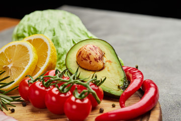 Fresh peeled avocado on a cutting board with tomatoes, peper and lemon