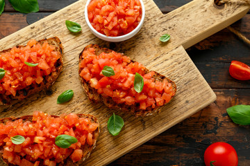 Tomato bruschetta seasoned with basil on a rustic wooden board