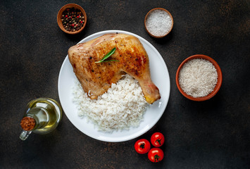 grilled chicken leg with spices and rice on a white plate on a stone background