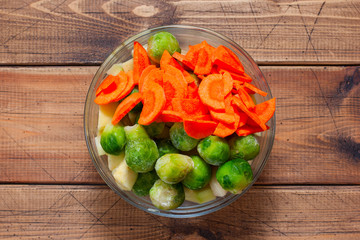 Step by step cooking of baked chicken with vegetables, step 4 - slicing carrots, adding brussels sprouts, selective focus