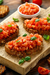 Tomato bruschetta seasoned with basil on a rustic wooden board