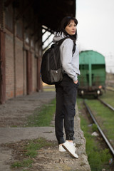 Fototapeta na wymiar young girl stands at the train station with a backpack in a train odd