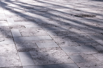 Stone pavement illuminated by morning sun rays. Shadows on natural stone pavement
