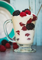 Fresh blueberry and raspberry with yogurt in an outdoor kitchen, rustic style. Healthy food in the summertime.
