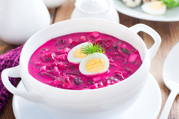 Traditional cold summer beetroot soup with vegetables in a white bowl, selective focus