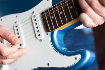 Close-up of man playing blue and white electric guitar