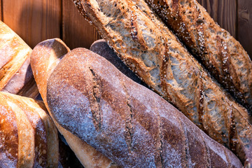 Fresh baked different breads on wooden background.