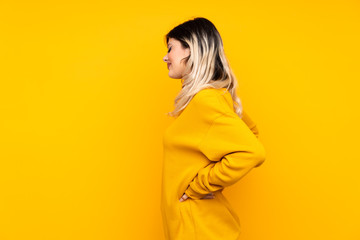 Obraz premium Teenager girl isolated on yellow background suffering from backache for having made an effort