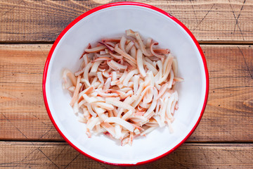 Step-by-step preparation of salad with calamari, eggs and fresh cucumbers and herbs, step 1 - chopped boiled squid, top view, selective focus