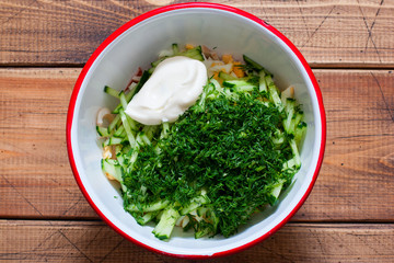 Step-by-step preparation of salad with calamari, eggs and fresh cucumbers and herbs, step 5 - adding mayonnaise, top view, selective focus