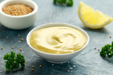 Dijon mustard in white bowl on rustic background