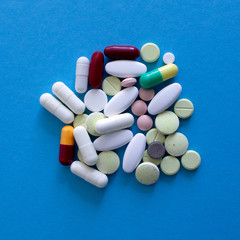 Colorful tablets and capsuls on blue background, macro shot