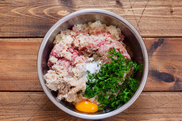 Step-by-step cooking of steamed turkey cutlets, step 3 - mixing the minced meat with herbs, egg and spices, top view, selective focus