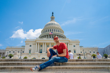 Young man sitting on the stairs by the United States Capitol in Washington.
