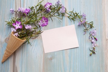 Spring concept. Floral background. Ice cream cone with rose flowers on a blue wooden background. Space for text