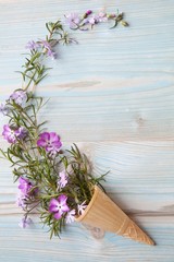 Spring concept. Floral background. Ice cream cone with rose flowers on a blue wooden background. Space for text