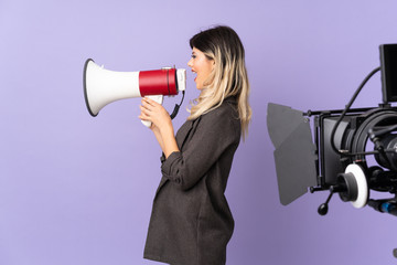 Reporter teenager girl holding a microphone and reporting news isolated on purple background shouting through a megaphone