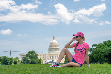 Young girl sitting on the grass by the United States Capitol in Washington.