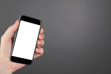Man hand hold smartphone on gray background. Copy space