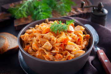 Braised cabbage with chicken breast in a clay bowl, selective focus