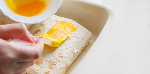 Woman's hand lubricates food by a kitchen brush
